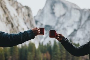 two person holding red mugs