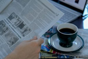 a person reading a newspaper with a cup of coffee