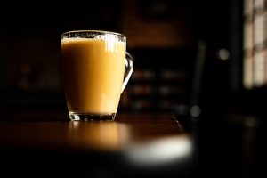 clear glass mug with brown liquid on brown wooden table